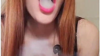 Smoking Redhead With Bright Makeup In A Black Leather Dress